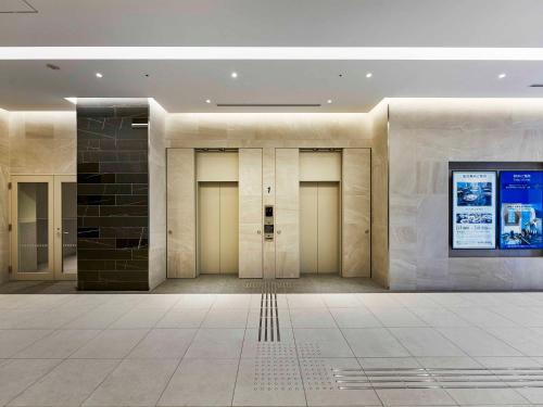 a row of doors in a building with a tile floor at Daiwa Roynet Hotel Wakayama in Wakayama