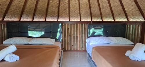 two beds in a room with bamboo walls at Uma Nirmala Aling-Aling in Singaraja