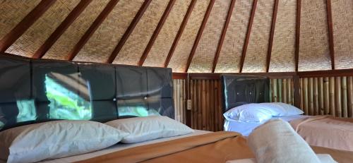 two beds in a room with a roof at Uma Nirmala Aling-Aling in Singaraja