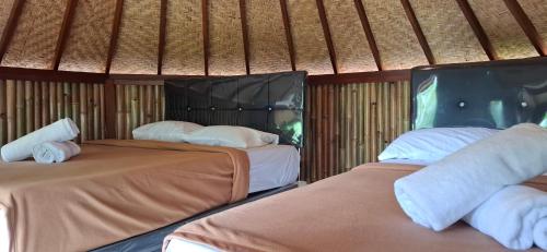 two beds in a room with a straw roof at Uma Nirmala Aling-Aling in Singaraja