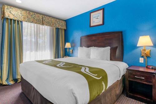 a hotel room with a large bed with blue walls at Quality Inn Sarasota North Near Lido Key Beach in Sarasota