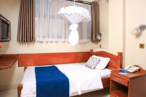 a bedroom with a bed with a dresser and a window at Paris Hotel in Nairobi