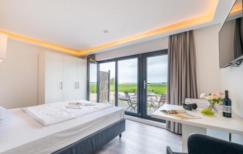 a hotel room with a bed and a desk and a balcony at Apartments Boddenblick in Sagard