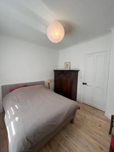 a white bedroom with a bed and a lamp at Maison La vieille vigne in Dieulefit
