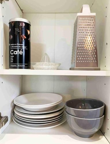 - une étagère de cuisine avec des assiettes et une canette de café dans l'établissement Studio TOURNETTE, à Chambéry