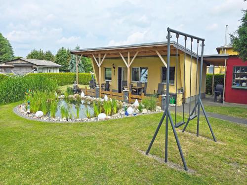 a small yellow house with a pond in the yard at Ferienhaus am Wiesengrund in Sagard