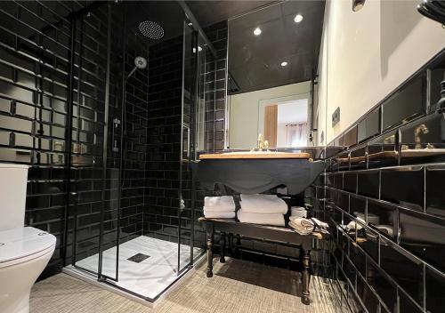 a black bathroom with a sink and a toilet at La Posada de Ruba in Biescas