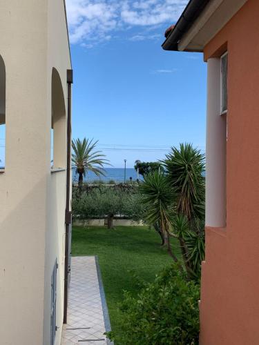 a hallway leading to a yard with palm trees at Residence Villa Carmen fronte mare a 50 mt in Pietra Ligure