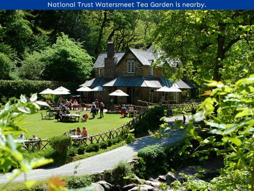 a building with people sitting in the grass in front of it at Chough's Nest Hotel in Lynton