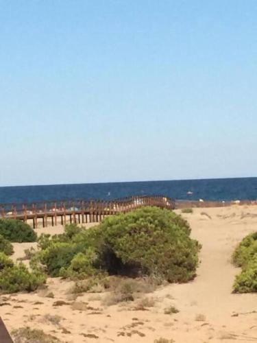 a sandy beach with a pier and the ocean at Preciosa Casita Boho Chic en la playa in Gran Alacant
