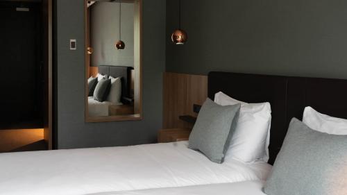 a bedroom with a bed with white pillows and a mirror at Hotel Gorinchem in Gorinchem