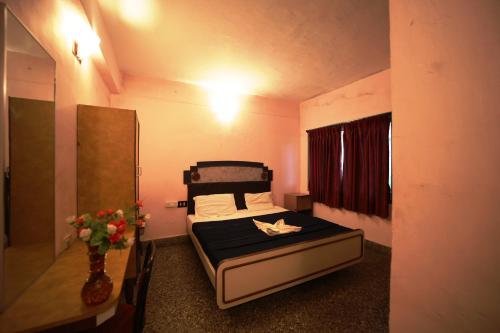 um pequeno quarto com uma cama e um vaso de flores em Jayaraj Residency em Kodaikānāl