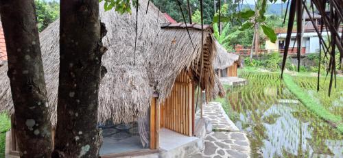 a small house with a thatched roof next to a tree at Uma Nirmala Aling-Aling in Singaraja