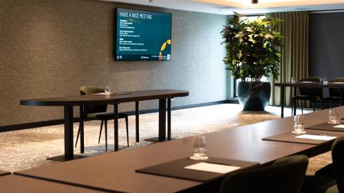 a conference room with tables and chairs and a screen at Hotel Gorinchem in Gorinchem