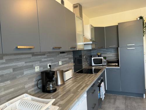une cuisine avec des placards gris et un comptoir dans l'établissement T4 Spacieux à proximité de la gare stationnement gratuit, à Saint-Étienne