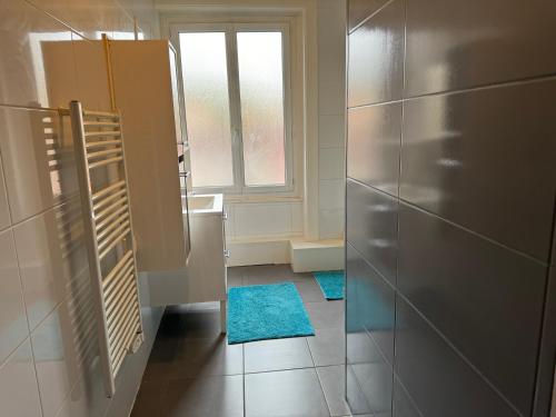 une cuisine avec un réfrigérateur et deux tapis bleus sur le sol dans l'établissement T4 Spacieux à proximité de la gare stationnement gratuit, à Saint-Étienne