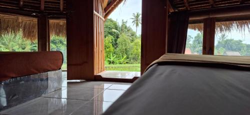 a bedroom with a bed and a large window at Uma Nirmala Aling-Aling in Singaraja