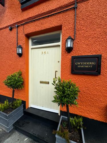 an orange building with a white door and a sign at The Bear Apartments in Llandovery