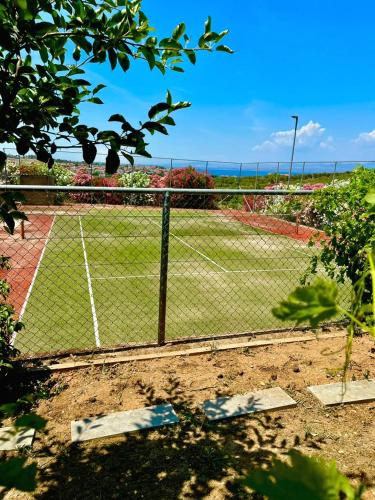 a tennis court behind a chain link fence at Lilian Luxury Villa Halkidiki in Nea Fokea