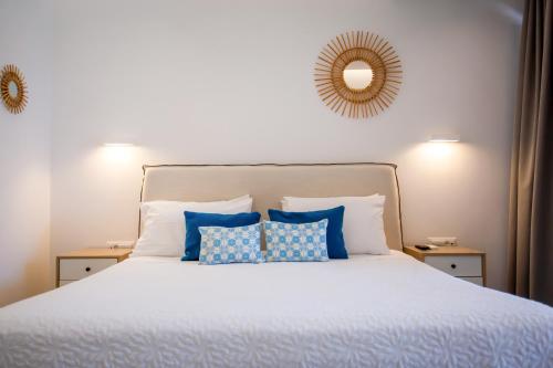 a bedroom with a white bed with blue pillows at VILLA PANAMERA Mykonos, Private Heaven, Supreme View! in Fanari