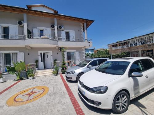 two cars parked in a parking lot in front of a building at Vila Soleil in Vlorë