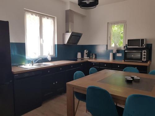 une cuisine avec une table en bois et des chaises bleues dans l'établissement Joli Appartement T3 La Mallerenga, à Vernet-les-Bains