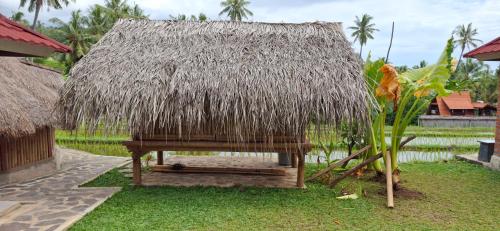a small hut with a grass roof on the grass at Uma Nirmala Aling-Aling in Singaraja