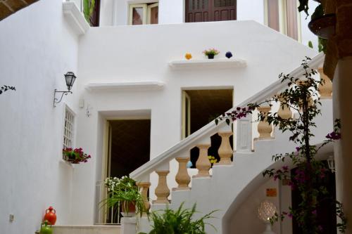 a staircase in a white house with flowers at Kàllistos Suites & Apartments in Gallipoli
