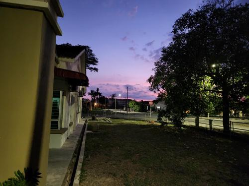 an empty street at night with a tree and a fence at The Bunker StudioStay in Arau