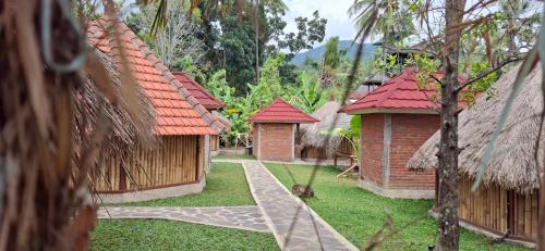 a row of houses with red roofs in a yard at Uma Nirmala Aling-Aling in Singaraja