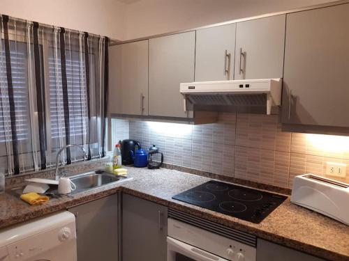 a kitchen with white cabinets and a stove top oven at El Marques Resort Townhouse in Puerto de Santiago