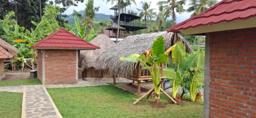 a house with a thatch roof and a yard at Uma Nirmala Aling-Aling in Singaraja