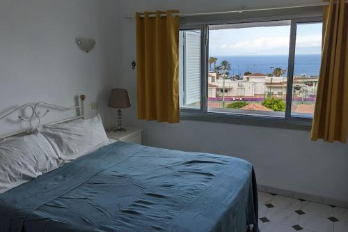 a bedroom with a bed and a large window at El Marques Resort Townhouse in Puerto de Santiago