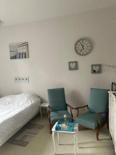 - une chambre avec deux chaises, un lit et une horloge dans l'établissement Appartement à louer Arcachon, à Arcachon