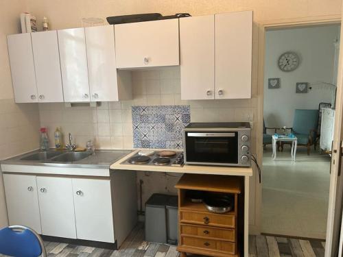 une cuisine avec des placards blancs et un four micro-ondes sur un comptoir dans l'établissement Appartement à louer Arcachon, à Arcachon