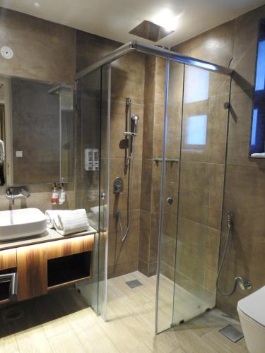 a shower with a glass door in a bathroom at Sapphire Sky Hotel in Dehradun