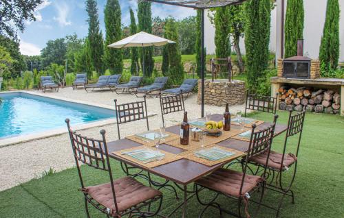 a wooden table and chairs with a table and a pool at La Bastide in Grignan