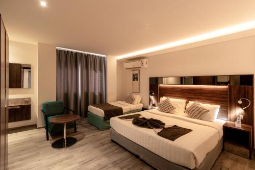 a hotel room with two beds and a chair at Barracuda Resort in Umm Al Quwain
