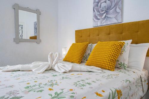 a bed with yellow and white pillows and a mirror at PANORAMIC VIEW Playa Paraíso in Adeje
