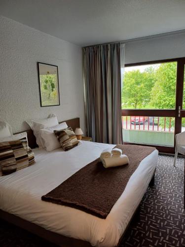 une chambre avec un grand lit avec une grande fenêtre dans l'établissement Hôtel-Restaurant La Belle Poule - Contact Hotel, à Rochefort