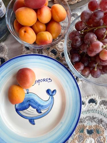 a plate with oranges on it next to bowls of grapes at Casa Baleia Laranja Ocean-Front in Madalena
