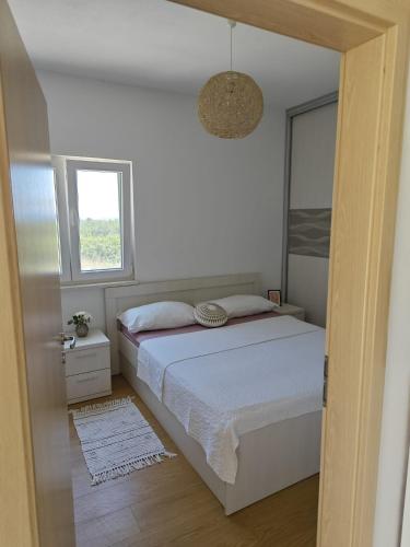 a white bedroom with a bed and a window at Happy garden house in Kožino