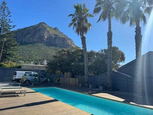 a pool with palm trees and a mountain in the background at THE PLACE Muizenberg in Muizenberg