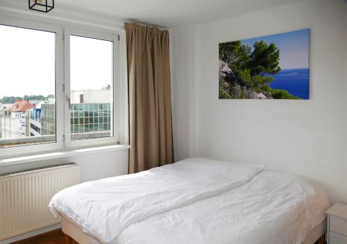 a white bedroom with a bed and two windows at Apartamento Buena Vista in Linz