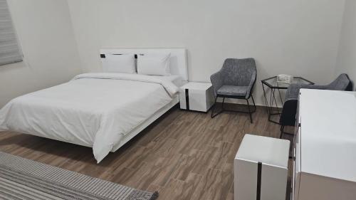 een witte slaapkamer met een bed en een stoel bij فندق السد الخليجى in Sīdī Ḩamzah