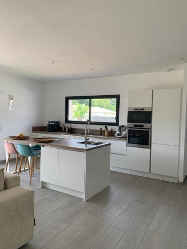 une cuisine avec des armoires blanches et un comptoir dans l'établissement La Ti Kaz, à Aureilhan