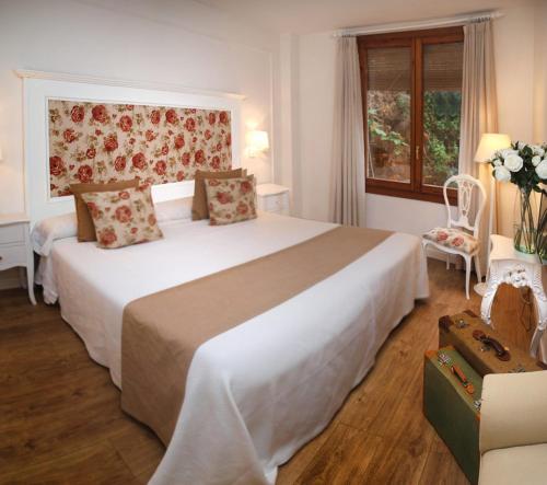 a bedroom with a large white bed and a window at Hotel Santa Maria de Alquezar in Alquézar