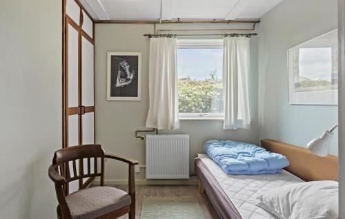 a bedroom with a bed and a chair and a window at Pet Friendly Home In Bandholm With Wifi in Bandholm