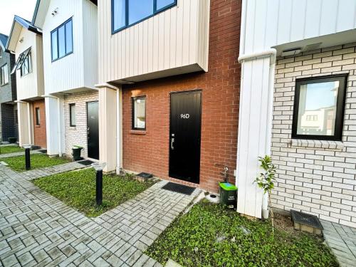 a brick house with a black door on it at Entire Modern 2-Bedroom Townhouse -10 min to Airport & Sylvia Park in Auckland