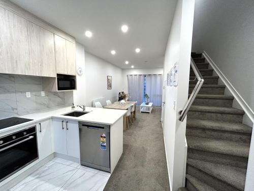 a kitchen and dining room with a staircase in a house at Entire Modern 2-Bedroom Townhouse -10 min to Airport & Sylvia Park in Auckland